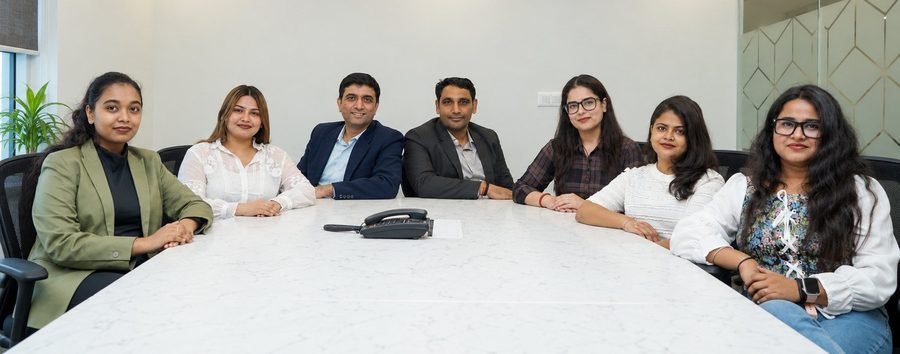 Seven members of the TNSL team seated around a conference table at the Gurugram office
